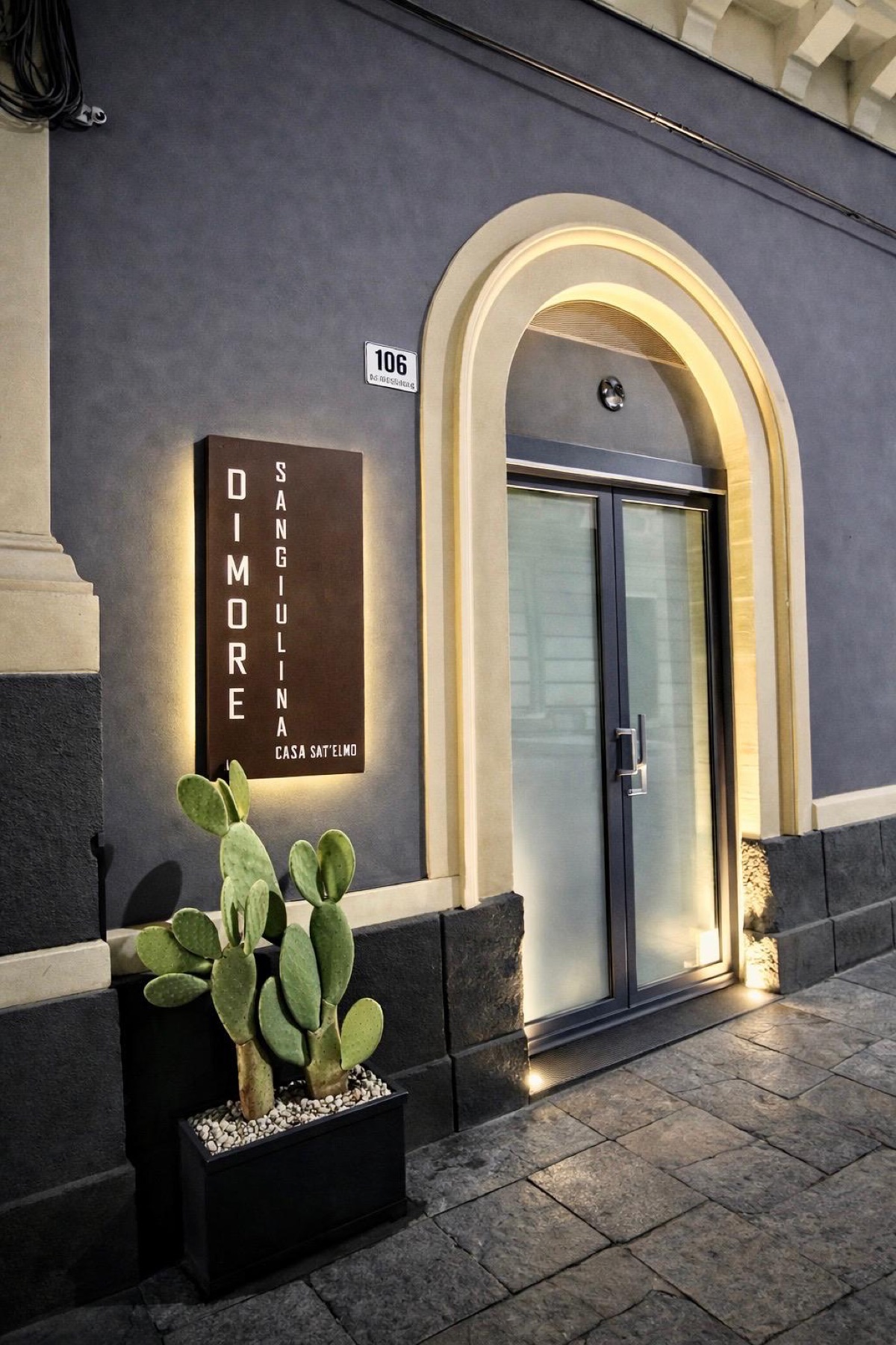 Ingresso serale di Casa Sant'Elmo con arco in pietra illuminato